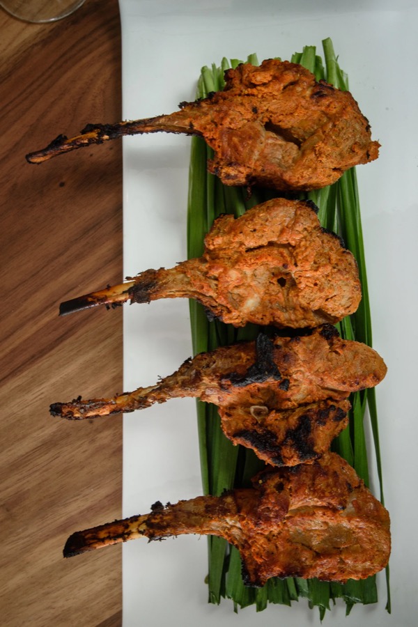 Four tandoori lamb chops on a bed of scallions, straight off the tandoor.